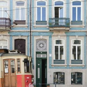 Old-fashioned tram passing by town houses in Porto